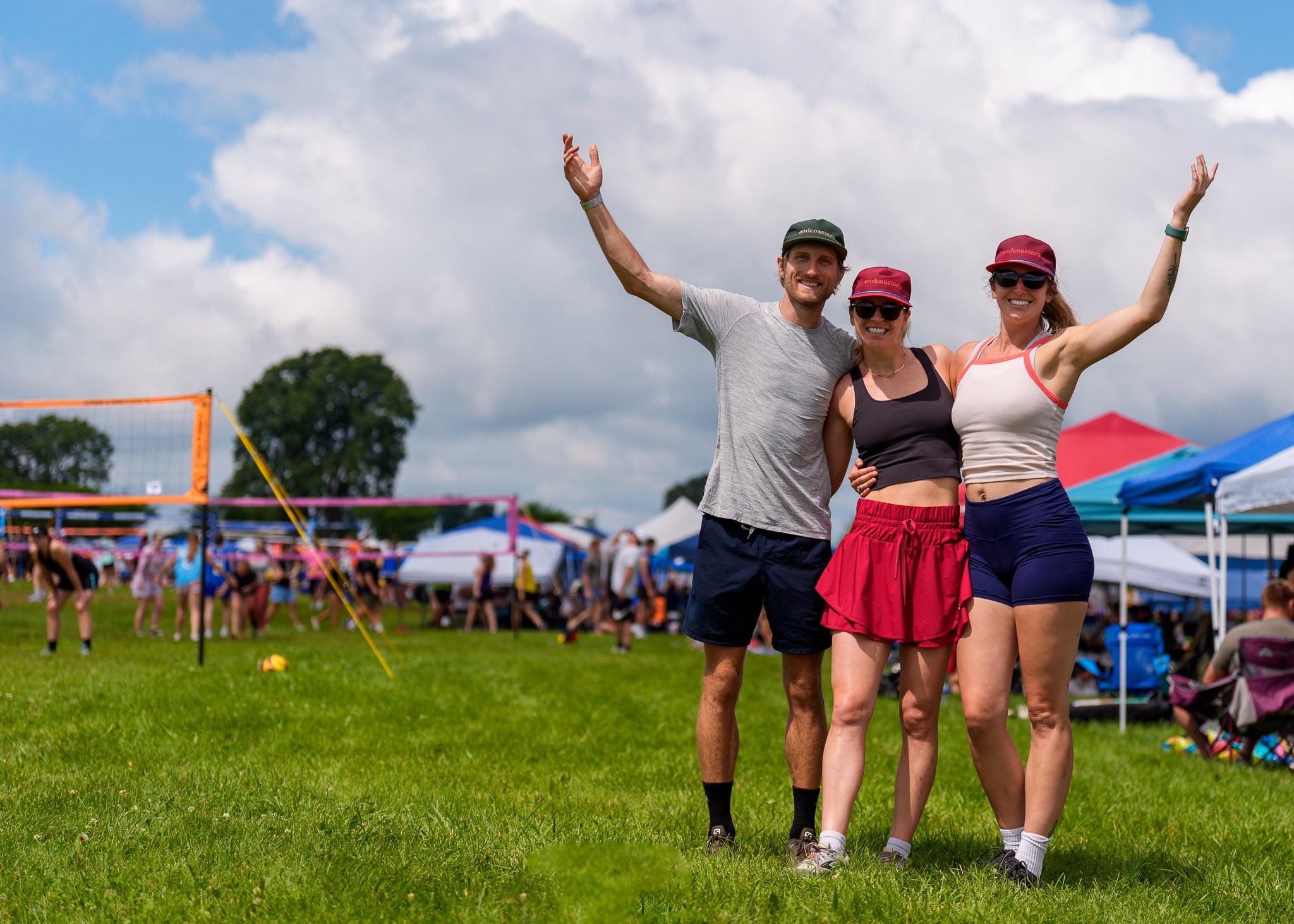 Three friends posing with arms raised at the Waupaca Boatride volleyball tournament in Oshkosh